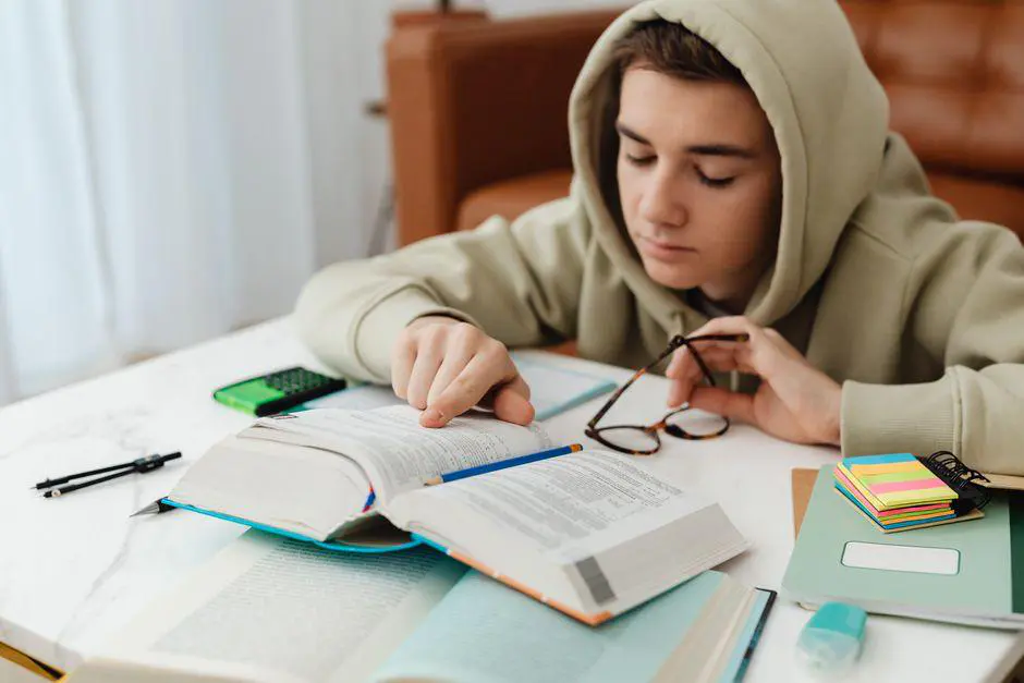Adolescent qui révise ses maths dans un manuel ouvert sur son bureau